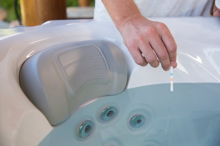 spa water care - man testing hot tub water with pH test strip 