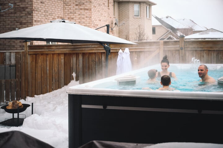 family playing in a outdoor swim spa in winter